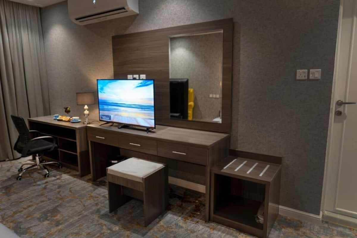 A hotel room with a desk, chair, and a large mirror.
