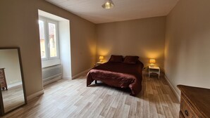 Un dormitorio con una cama grande, dos lámparas de noche, un tocador de madera y una ventana con persianas.