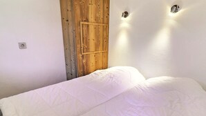 Ein Schlafzimmer mit Holztür, einem Bett mit weißer Bettwäsche und zwei Wandleuchten.