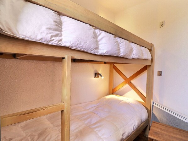 Ein Stockbett mit Holzrahmen und weißer Bettwäsche.