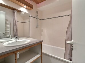 Une salle de bain équipée d’un lavabo, d’un miroir, d’une douche et d’une baignoire.
