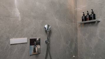 A bathroom with a shower, a mirror, and a shelf with toiletries.