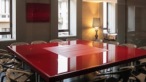A conference room with a long red table, several chairs, a lamp, and large windows with a view of buildings outside. - 10 KEYS MILANO (Milan)