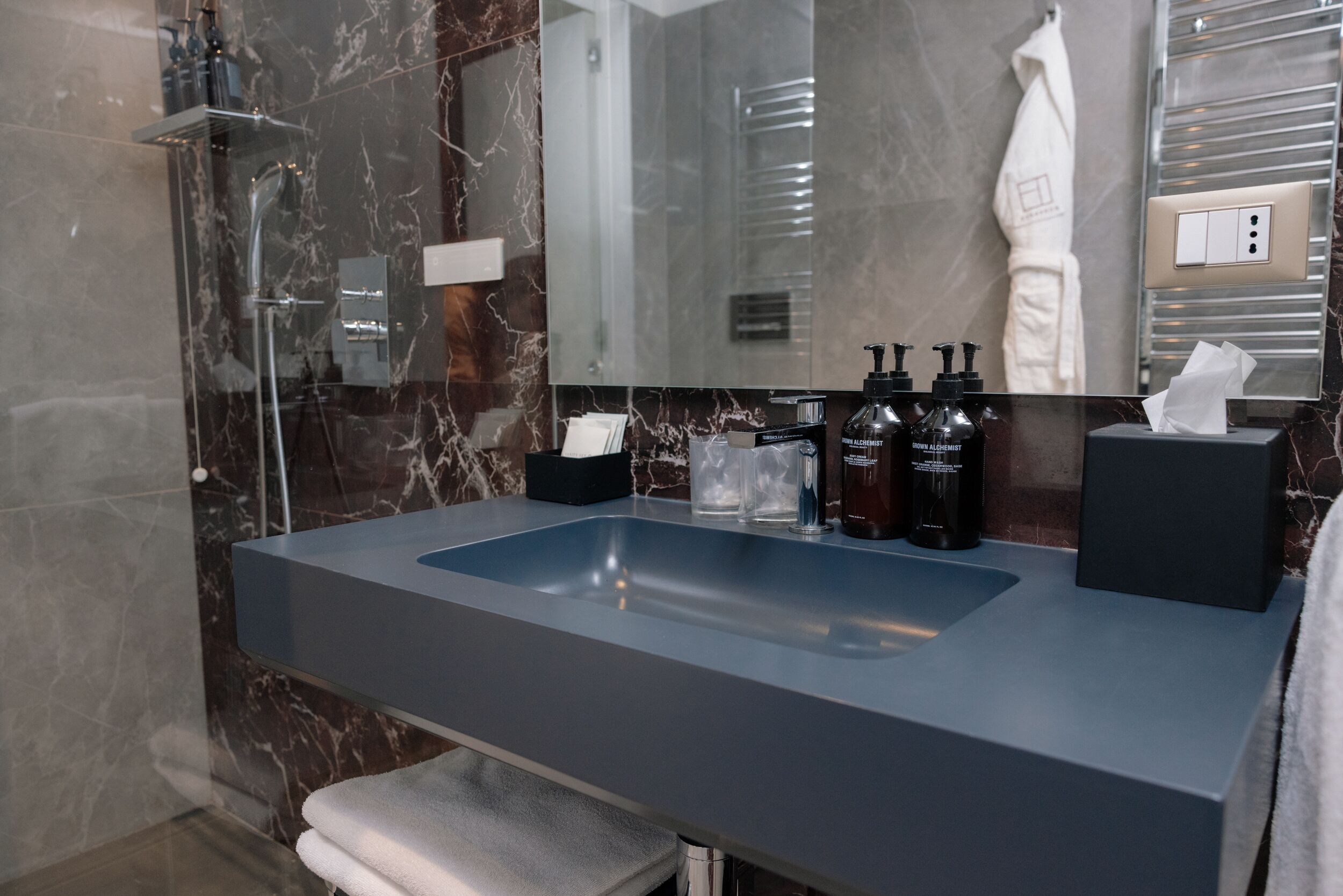 A modern bathroom with a large marble sink, a glass shower enclosure, and a towel rack.