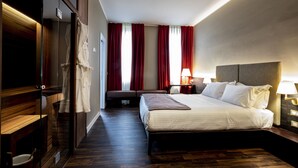 A hotel room with a bed, bedside tables, a robe, a seating area, and a view of the outside through large windows. - 10 KEYS MILANO (Milan)