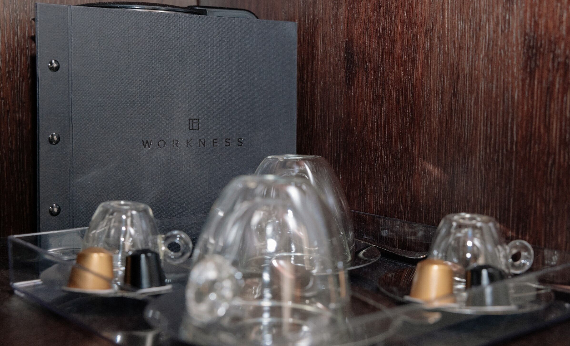A dark grey binder with the word "WORKNESS" embossed on it, placed on a wooden surface.
