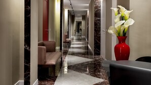 A modern hotel lobby with a marble floor, a reception desk, a seating area, and a vase of white flowers. - 10 KEYS MILANO (Milan)