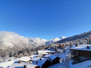 Un borgo montano innevato con edifici in legno e un cielo azzurro limpido.