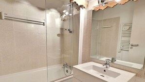 Une salle de bain moderne avec une douche à parois de verre, un lavabo blanc et un grand miroir.