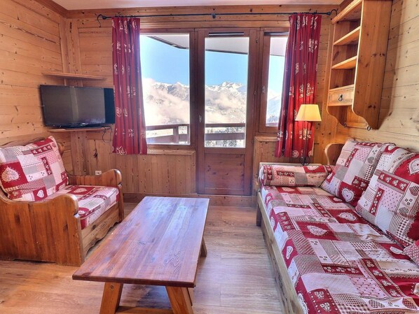 Uma cabana de madeira com um banco, uma mesa e um sofá com almofadas estampadas.