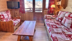 Une cabane en bois avec un banc en bois, une table et un canapé agrémenté de coussins à motifs.