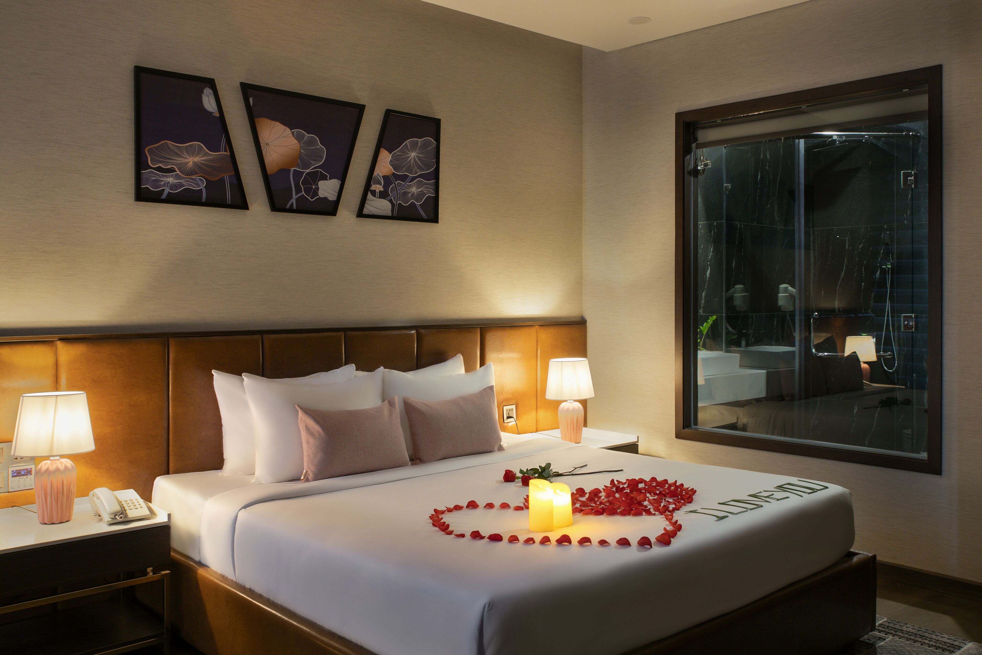 A hotel room with a bed, two bedside lamps, a nightstand with a phone, and a window with a view of the outside.