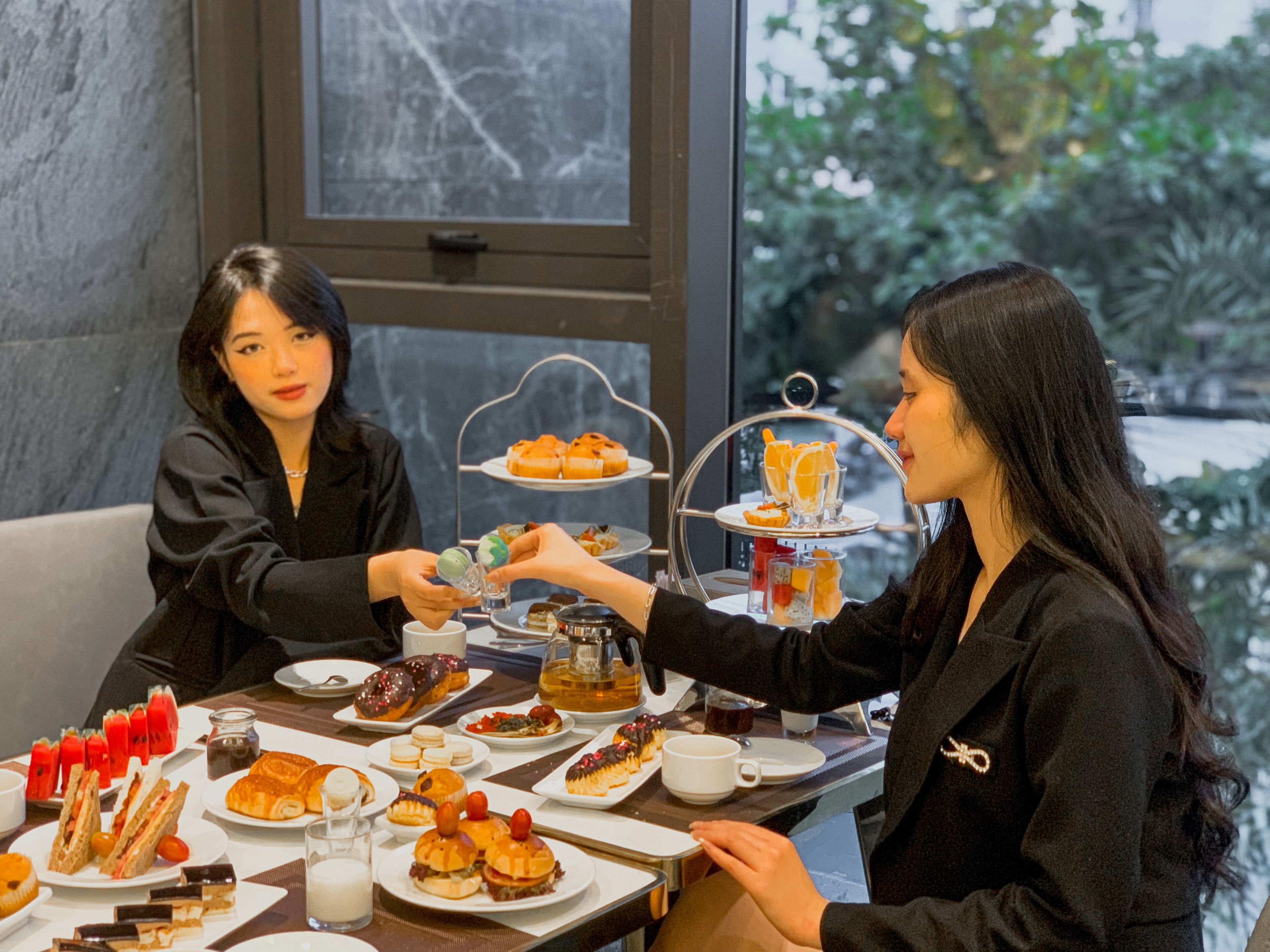 A dining table with various pastries and desserts, a coffee pot, and a tea set.