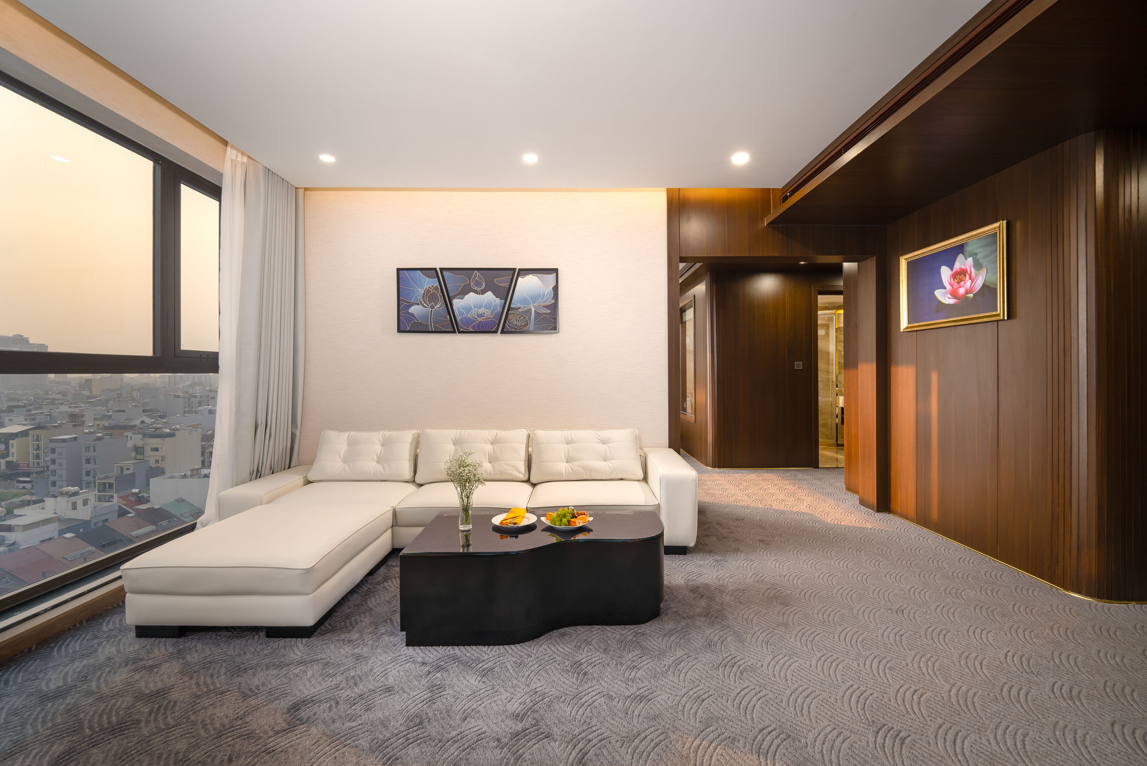 Una sala de estar moderna con un sofá modular, una mesa de centro negra y vistas a la ciudad a través de grandes ventanales.