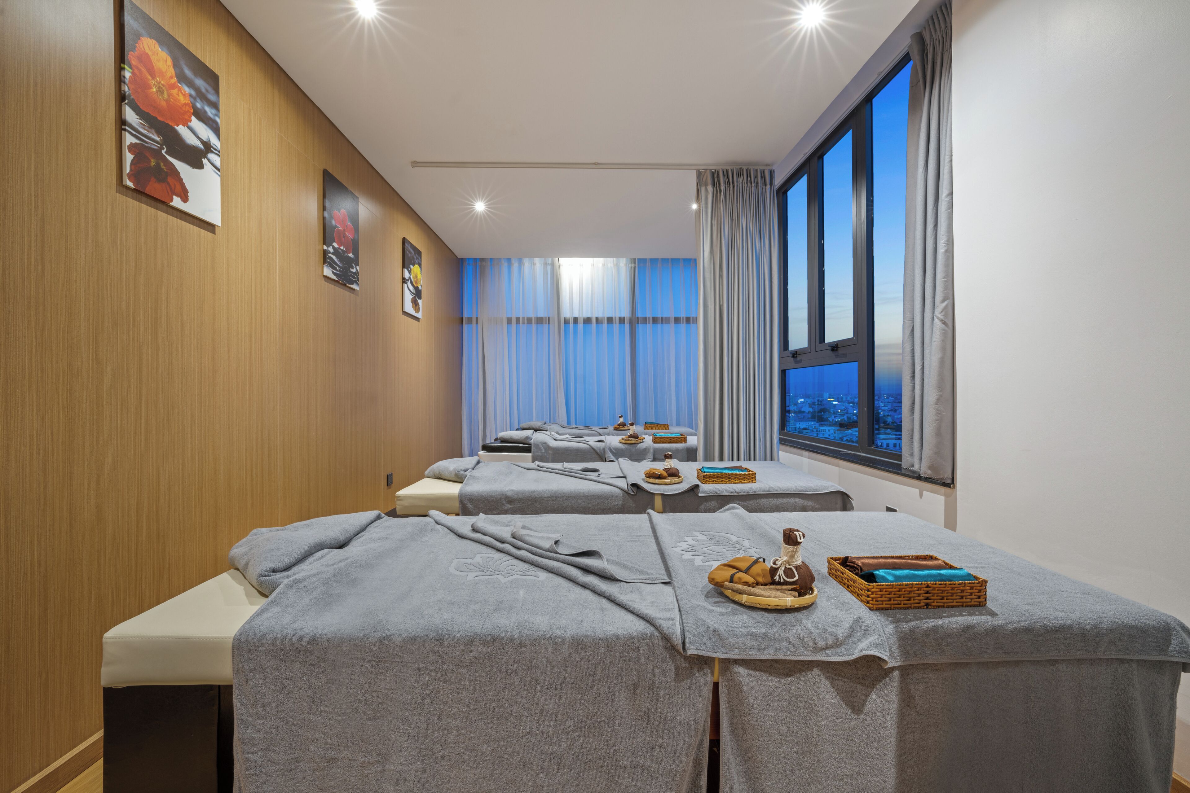 A spa room with massage tables, towels, and a view of the city.