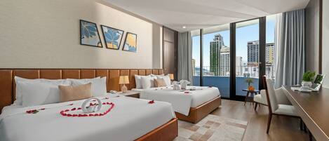 A hotel room with two beds, a desk, and a view of the city.