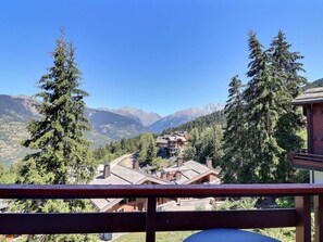 Eine Berglodge mit mehreren Gebäuden, umgeben von hohen Nadelbäumen und freiem Blick auf ferne Berge.