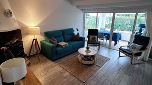 A spacious living room with a teal sofa, a round coffee table, and a ceiling fan.