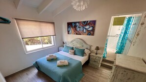 A bedroom with a bed, bedside tables, a painting, a window with a blind, and a wooden floor.