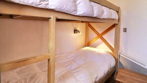 A bunk bed with a wooden frame and white bedding. - Comfortable 2-Room + Alcove Apartment, Ski-in/Ski-out (La Tania)