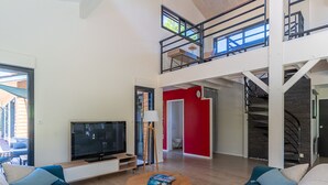 Ein großzügiges Wohnzimmer mit einem großen Flachbildfernseher, bequemen Sitzgelegenheiten und einer Treppe zu einer oberen Ebene.
