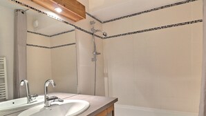 A bathroom with a sink, mirror, shower, and bathtub.