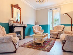 A room with a fireplace, two armchairs, a coffee table, and a patterned rug.