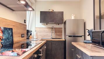 Een moderne keuken met een inbouwoven, een roestvrijstalen koelkast en een houten aanrecht.