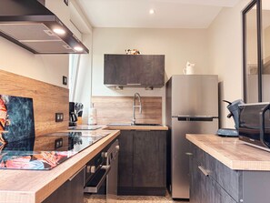 Une cuisine moderne dotée d’un four encastré, d’un réfrigérateur en acier inoxydable et d’un plan de travail en bois.