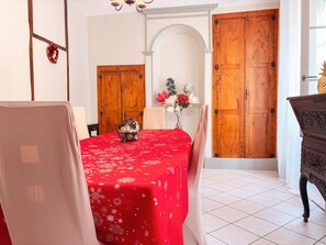Un coin repas avec une nappe rouge, des portes en bois et un lustre.