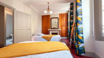 Een slaapkamer met twee bedden, een houten garderobe, een spiegel en een raam met gordijnen.