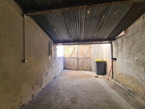 A narrow corridor with a concrete floor, a metal roof, and a wooden gate at the end.
