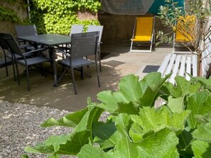 An outdoor seating area with a table and chairs, surrounded by greenery.
