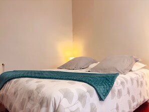 A bed with a patterned bedspread, two pillows, and a teal blanket.
