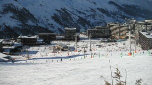 En skidort med flera byggnader, skidliftar och ett snötäckt landskap med berg i bakgrunden.