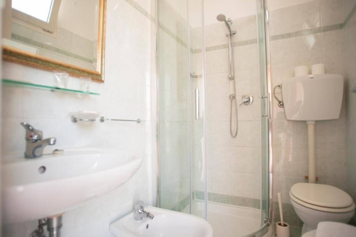 A bathroom with a glass-enclosed shower, a sink, and a toilet.