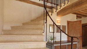 A staircase with wooden railings and beige steps leading to a landing area with a wooden cabinet and a potted plant.