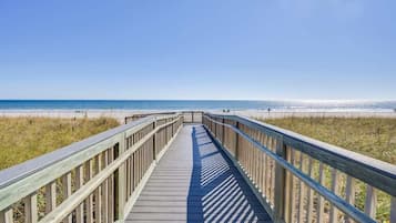 A wooden boardwalk leading to a beach with clear skies.