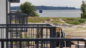 Una obra en construcción con una excavadora amarilla y un barco azul en un río.