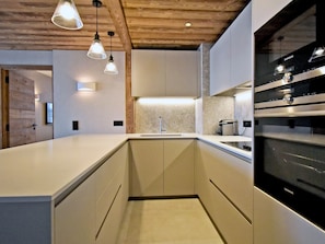 A modern kitchen with a built-in oven, a sink, and pendant lighting. - Luxury apartment, 3 bedrooms, terrace, concierge, central Méribel (Méribel)