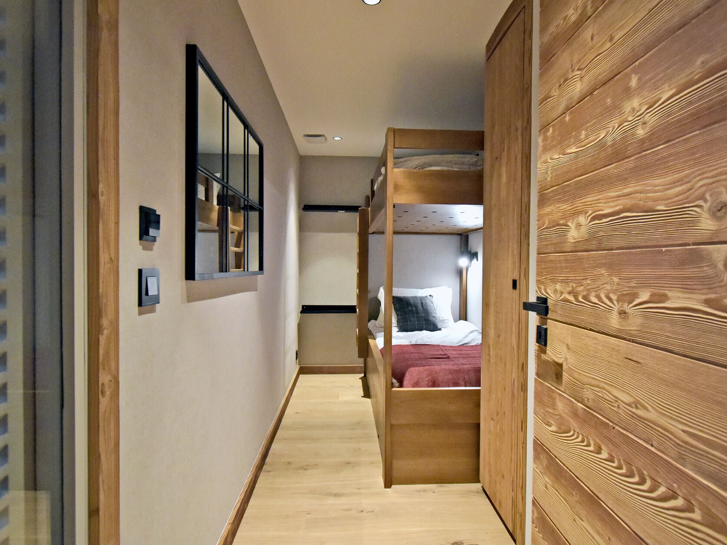 Ein schmaler Flur mit einem Holzbettgestell und einem Kleiderschrank.