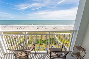 A balcony with a view of a beach and ocean.