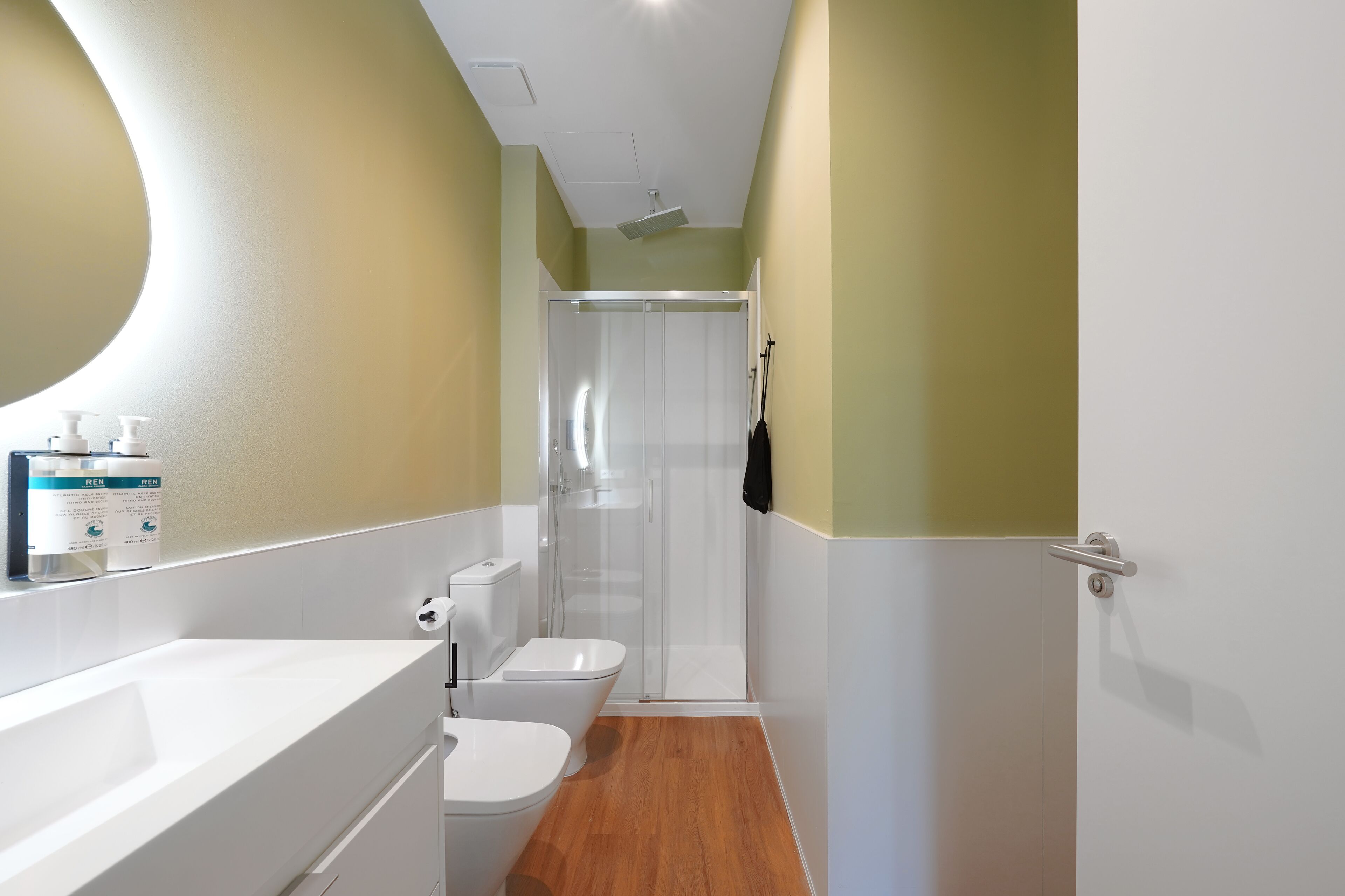 A modern bathroom with a white sink, toilet, and shower stall.