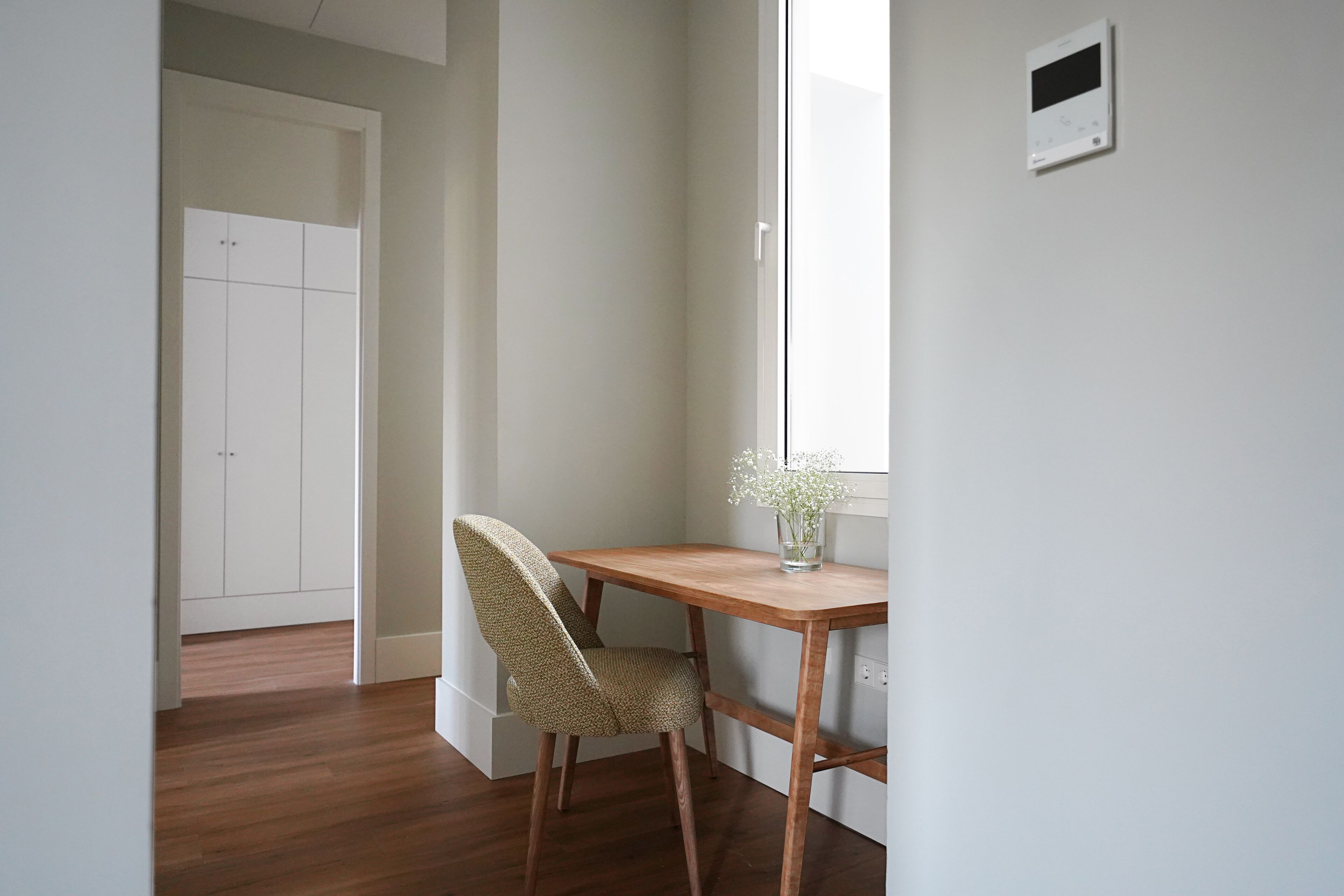 A room with a wooden desk, a chair, a window, and a door.