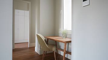 A room with a wooden desk, a chair, a window, and a door.