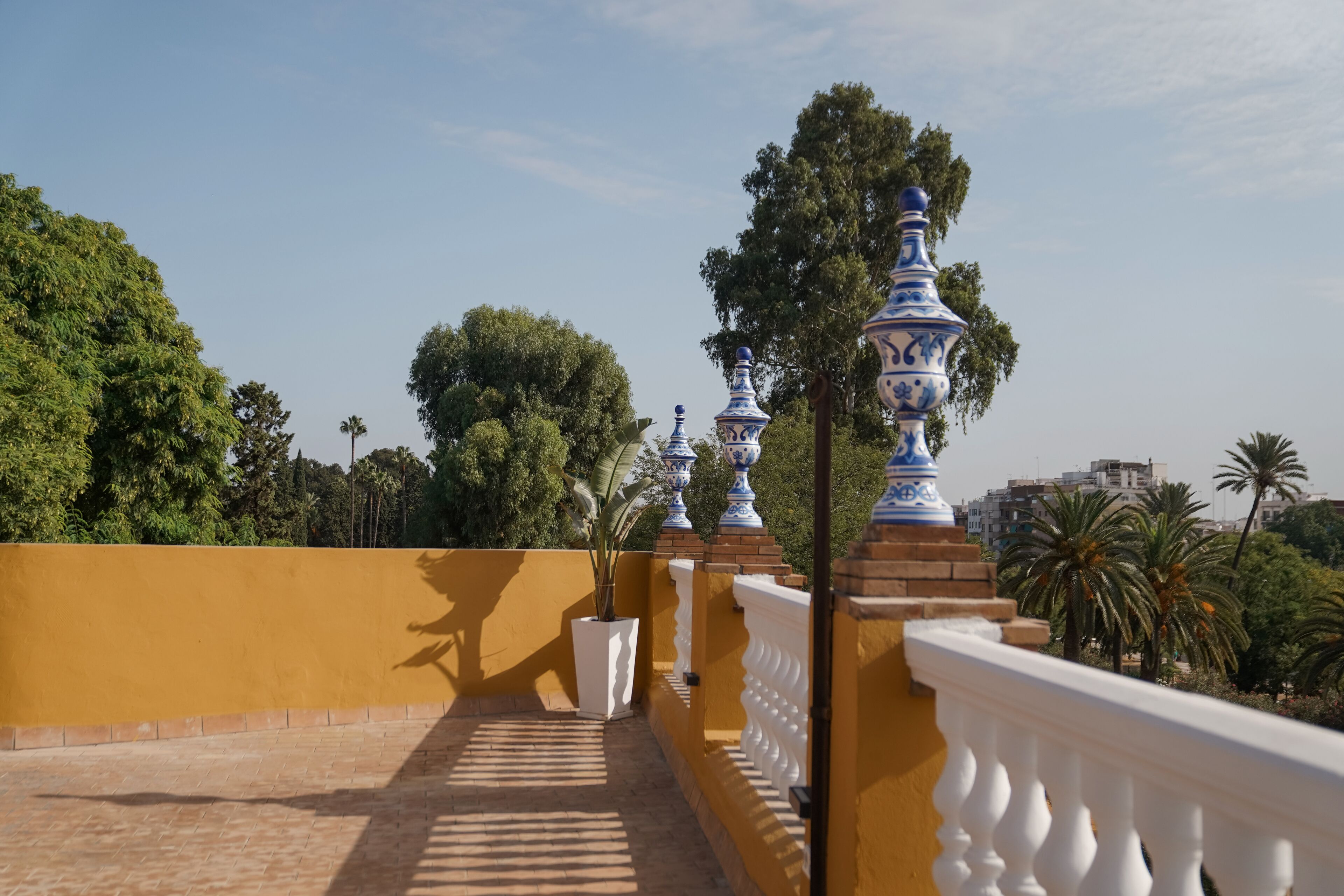 Un balcone con parete gialla, balaustra bianca e vasi blu e bianchi decorativi.