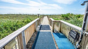 Un paseo marítimo de madera que conduce a una playa con cielo despejado.