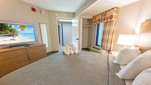 Habitación de hotel con una cama grande, un televisor de pantalla plana, un aparador de madera y un baño visible a través de una puerta abierta.