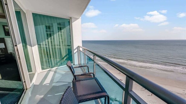 Un balcone con ringhiera in vetro che si affaccia su una spiaggia.