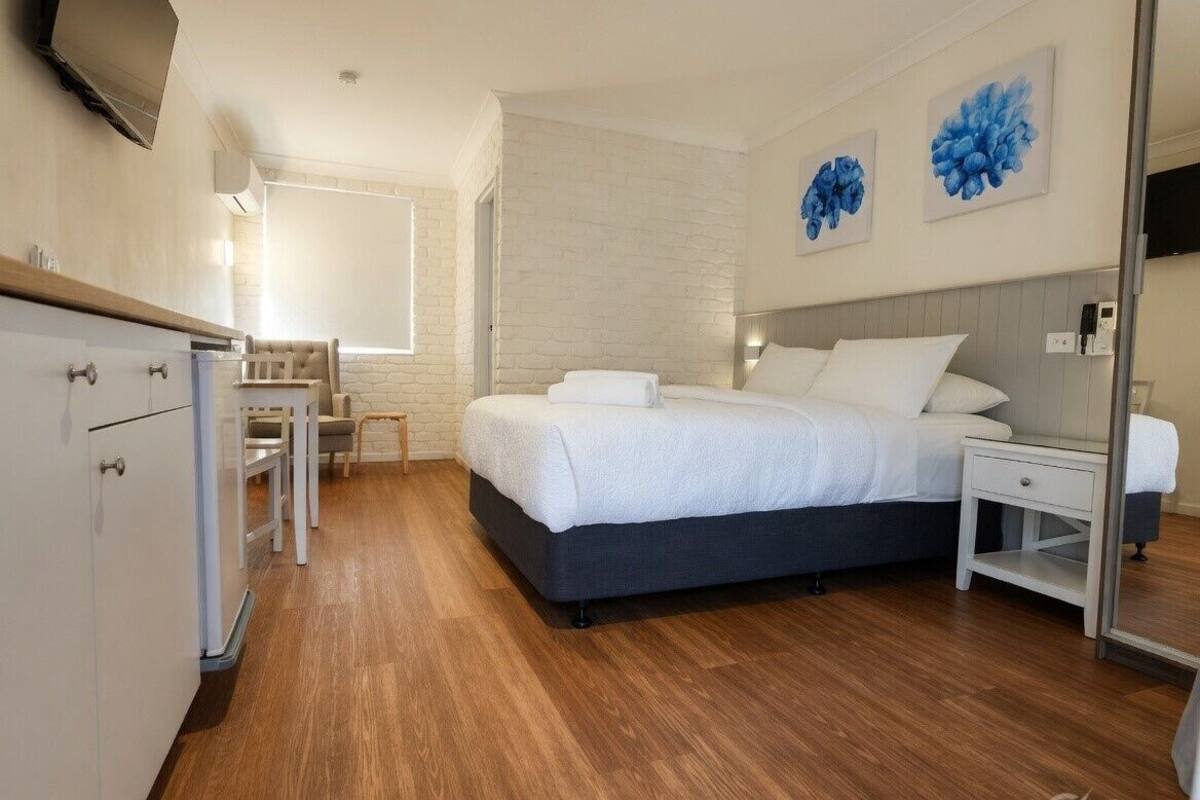 A bedroom with a bed, bedside tables, a desk, and a chair.
